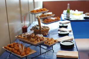 Buffet table with trays of assorted pastries on a blue tablecloth, ready for guests.